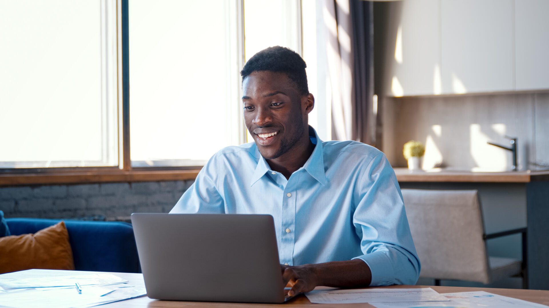 Smiling young man using laptop meeting in video call at home office